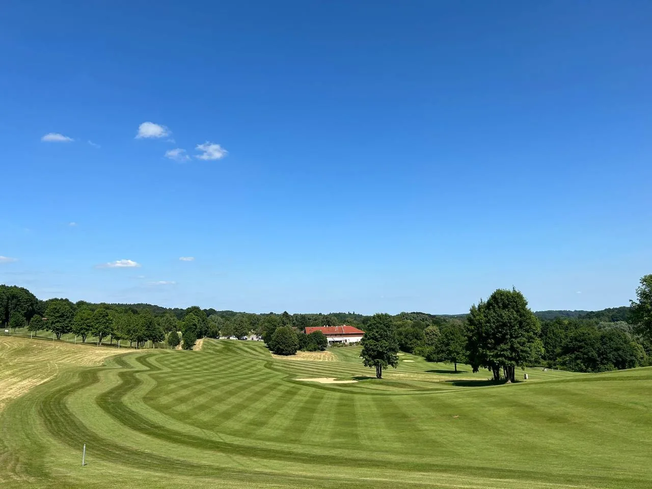 Panorama pola golfowego z wykoszonymi pasami fairwayu