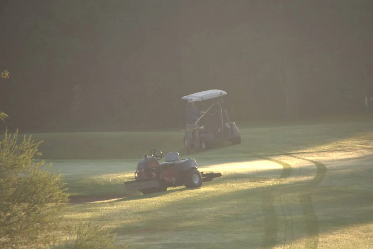 Maszyny pracujące na polu golfowym w porannym świetle