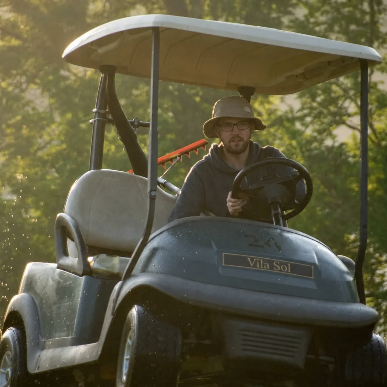 Greenkeeper jadący pojazdem technicznym podczas pracy na obiekcie